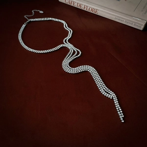 Macro shot of silver tassel necklace with rhinestones on red velvet with vintage book