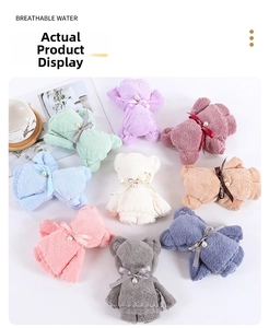 Macro detail of coral fleece bear towel with pearl bow decoration and ribbon text