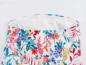 Detailed macro view of the elastic neckline and vibrant floral print on white fabric