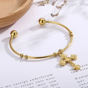 Close-up of golden rose cross cuff bracelet with floral relief on vintage paper