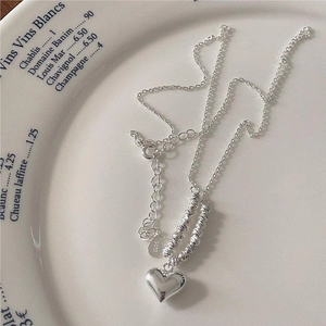 Minimalist S925 sterling silver heart pendant necklace on a decorative white ceramic plate