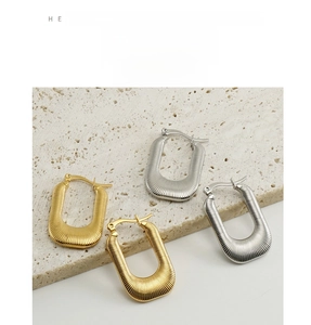 Detailed view of U-shaped gold and silver earrings with fine vertical stripe texture