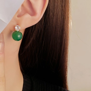 Gros plan de boucles d'oreilles dorées avec zircon blanc et pendentif rond vert sur un mannequin