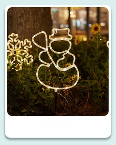 Outdoor solar snowman stake light with warm white LED glowing in garden landscape