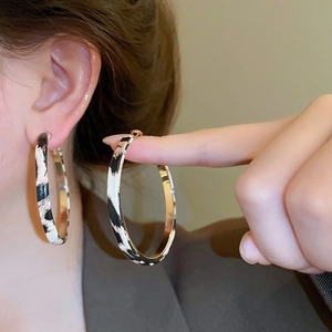 Detailed view of large leopard print hoop earrings with golden inner metal finish