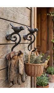 Detalle de ganchos de hierro fundido con pájaros sujetando guantes y cesta en madera