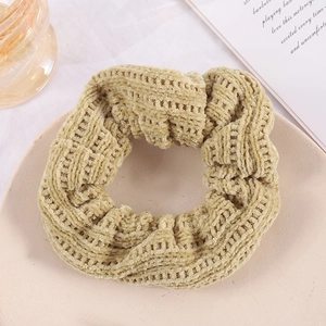 Detailed view of a beige corduroy scrunchie on a decorative plate with soft lighting