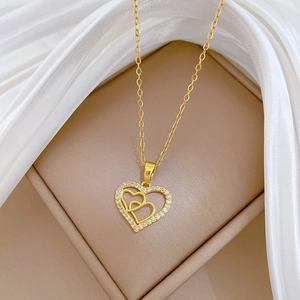Detail of gold double heart pendant featuring diamond-encrusted outer edge on silk