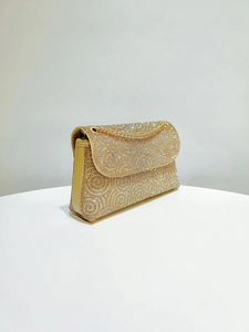 Close-up of sparkling gold rhinestone handbag with elegant metal chain shoulder strap