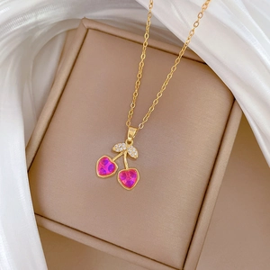 Macro view of gold-tone cherry pendant necklace with vibrant pink crystals on silk