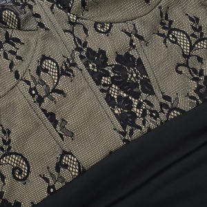 Detail of elegant black floral lace stitching on a chic beige and black mini dress