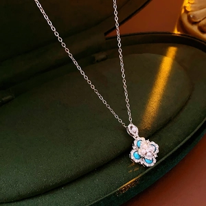 Detail of floral pendant necklace with pearls and blue stones on dark velvet