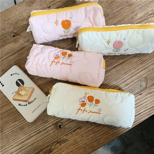 Close-up of quilted floral pencil cases with tulip embroidery and Good Luck text