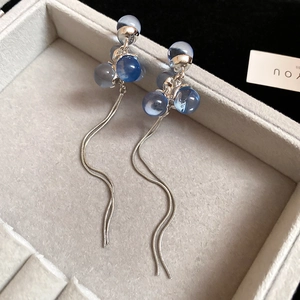 Detail of blue resin bead earrings with silver snake chain tassels in a jewelry box