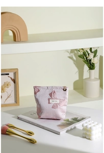 Dettaglio della borsa trucco rosa con fiocchi e cerniera a fiore su una rivista