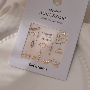 Golden 3D nail art stickers with heart patterns and rhinestone gems on white ceramic