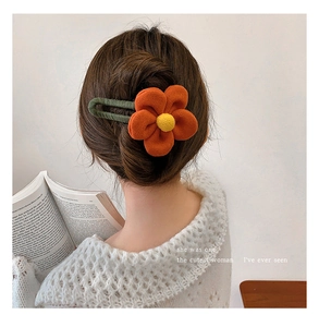 Detail of orange floral plush hair claw clip worn on head for elegant autumn hair styling
