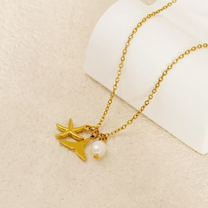 Close-up of gold nautical necklace with starfish, whale tail and white pearl charms