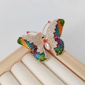 Macro view of crystal butterfly brooch with colorful mosaic enamel and pink pear gemstone