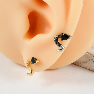 Macro view of gold and silver snake stud earrings with black teardrop stones on ear model