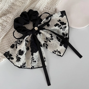 Close-up of elegant floral print ribbon scrunchie with a small gold metal charm detail