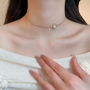 Detail of rose gold double-layered necklace featuring hollow flower and pearl pendant
