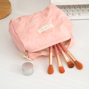 Pink butterfly embossed cosmetic bag set with matching makeup brushes on a desk