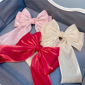 Detailed view of large three-layer ribbon hair clips in pink, gold and red pearl satin