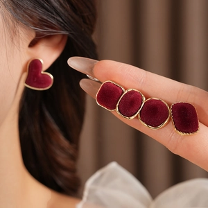 Detail of red velvet and gold geometric earrings set worn on ear for elegant style