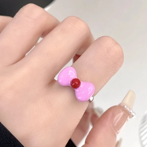 Pink enamel bow ring with red bead center on index finger for women's jewelry style