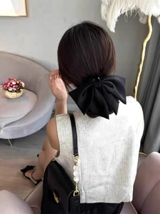 Rear view of model wearing oversized black satin bow hair clip for elegant hair styling