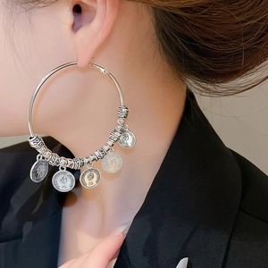 Detail of silver hoop earrings featuring vintage coin charms and engraved metal beads