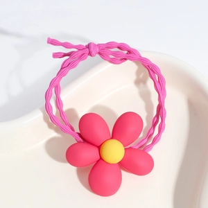 Detailed macro view of a pink floral hair tie with yellow core on a white ceramic tray