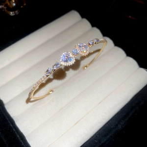 Close-up of gold-plated heart zircon bracelet resting in a beige velvet jewelry box