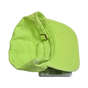 Detail view of fluorescent green cotton baseball cap showing 90.4g weight on scale