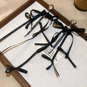 Détail macro de boucles d'oreilles à nœud élégant avec de longs glands en cristal et perle