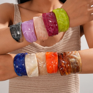 Macro detail of stacked colorful acrylic bangles with elegant marble textures on wrist