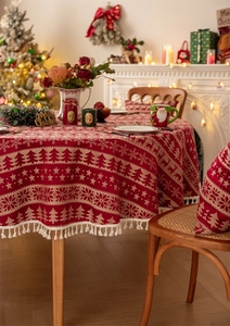 Detail of red Christmas tablecloth with white fringe and festive reindeer patterns