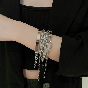 Detail of silver layered bracelet set featuring curb and oval chains on a model wrist