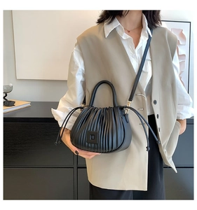 Detail of black pleated bucket bag with square buckle and adjustable shoulder strap