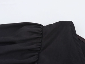 Dettaglio ravvicinato della manica a pieghe e delle cuciture di qualità sulla maglia nera a V