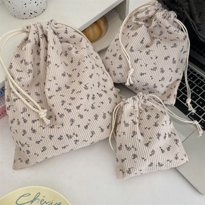 Three sizes of floral corduroy drawstring storage bags on a clean desk workspace