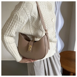 Close-up of the vintage leather crescent hobo bag with gold buckle on a knitted sweater