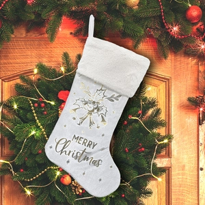White Christmas stocking with gold Merry Christmas text hanging on a festive wooden door