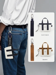 Dettaglio del portachiavi mini borsa tote in tela con clip metallica e cinturino da polso