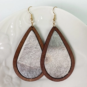 Detail view of teardrop leopard print wood earrings on a white ceramic plate