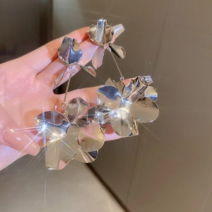 Close-up of silver metal flower earrings with 3D petals and sparkling light effects