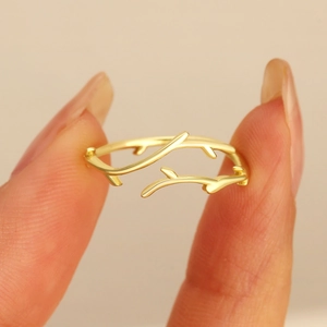 Close-up of golden branch-shaped open ring with intricate natural wood texture