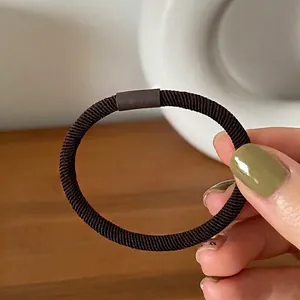 Close-up of coffee brown thick elastic hair tie with textured twill weave and smooth connector