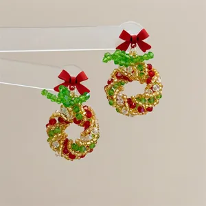 Detail of handmade Christmas wreath earrings with colorful beads and a red bow decoration